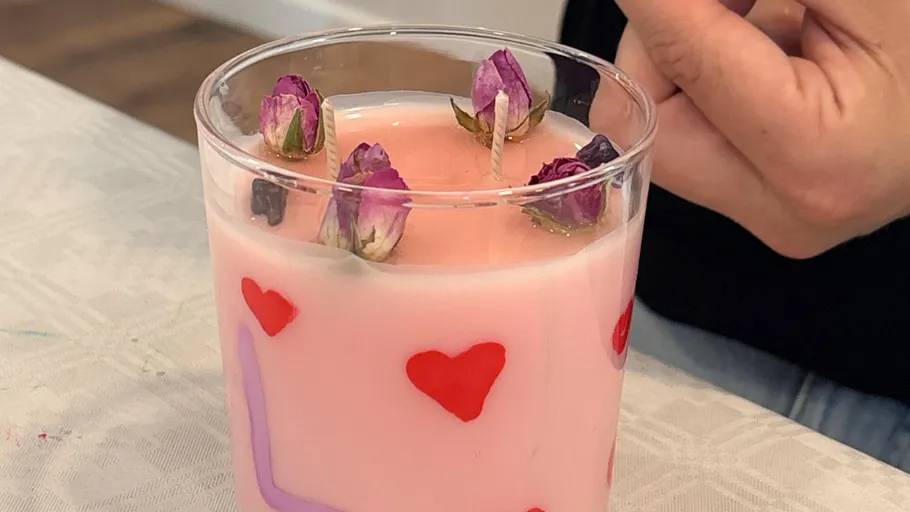 Rosa Kerze mit Rosenknospen auf Tisch.