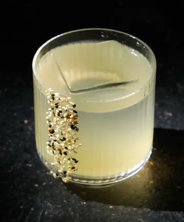 Glas mit Cocktail und Sesamdeko verziert.