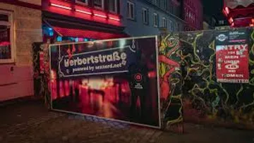 Eingangsschild in lebhafter Straße bei Nacht.