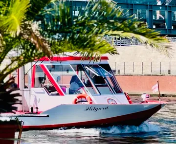 Boot fährt auf Wasser, Gebäude dahinter.