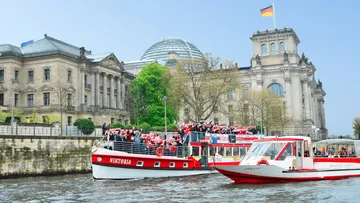 Two red boats on river near historic building.