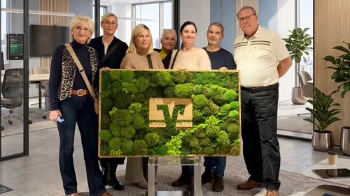 Gruppe zeigt Pflanzenkunstwerk im modernen Büro.