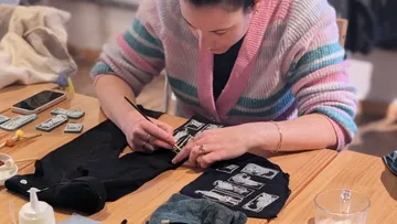 Woman painting designs on clothing indoors.