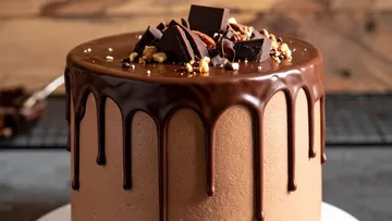 Schokoladenkuchen mit tropfendem Guss auf Teller.