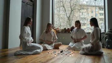 Four women meditating in a bright room.