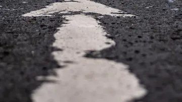 Pfeil auf nasser Asphaltstraße gemalt.