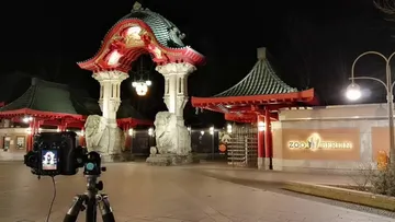 Stativkamera fotografiert Zoo Berlin Tor nachts.