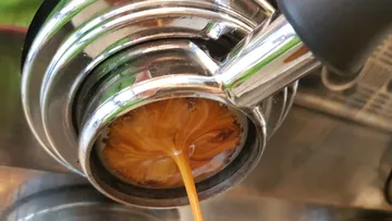 Espresso fließt aus einem Siebträger, Kaffeemaschine.
