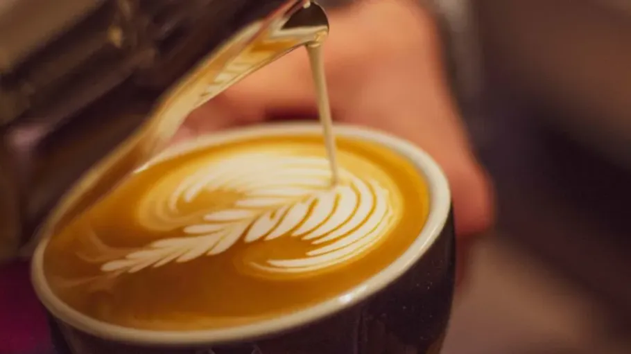 Barista gießt Latte Art in Kaffeetasse.
