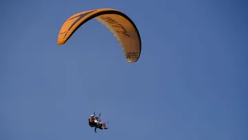 Gleitschirmflieger fliegt im klaren blauen Himmel.
