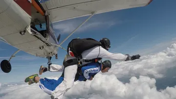 Zwei Fallschirmspringer springen aus Flugzeug.