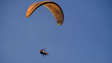 Gleitschirmflieger unter klarem blauen Himmel.
