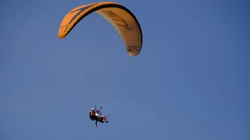 Gleitschirmflieger schwebt im klaren blauen Himmel.