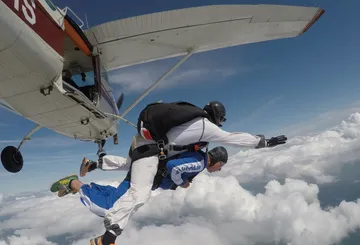 Tandem-Fallschirmspringer springen aus Flugzeug.