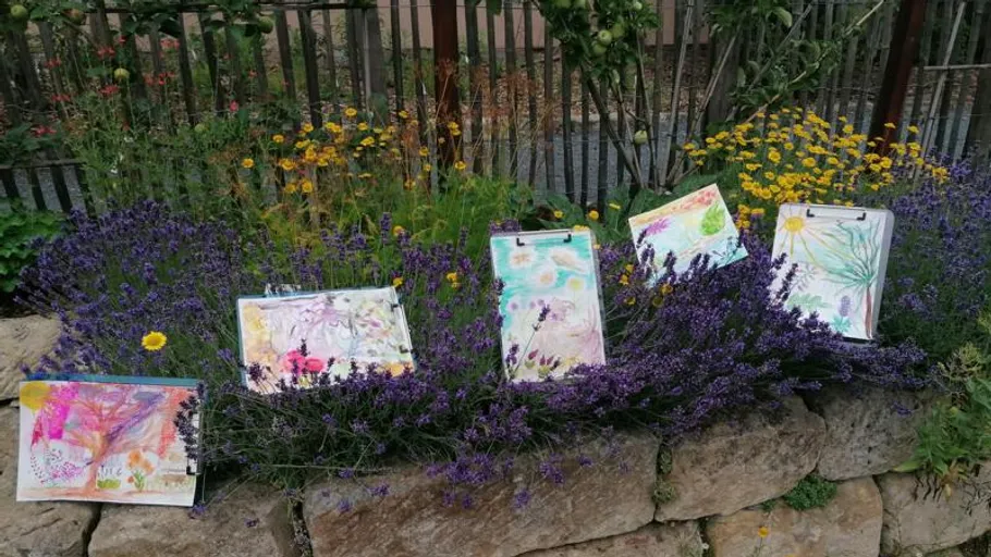 Colorful paintings displayed on lavender bushes.
