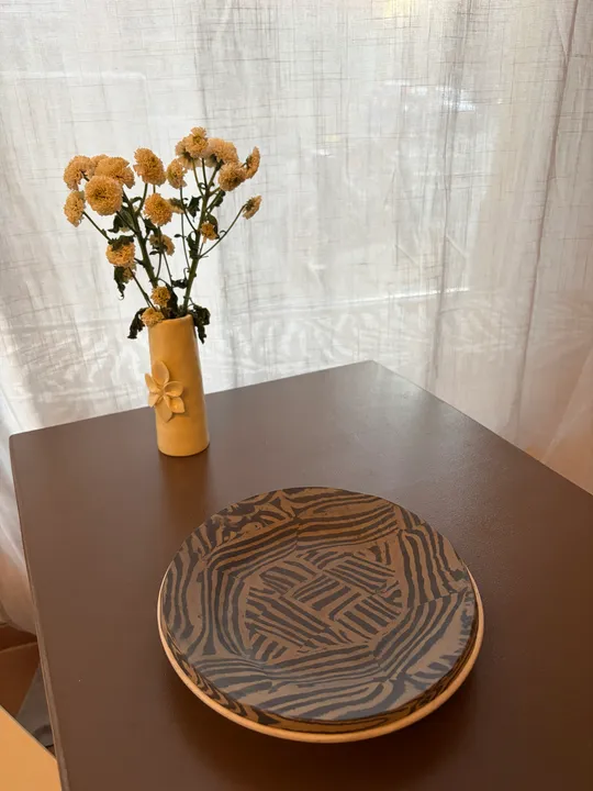 Dekorativer Teller und Vase auf Holztisch.