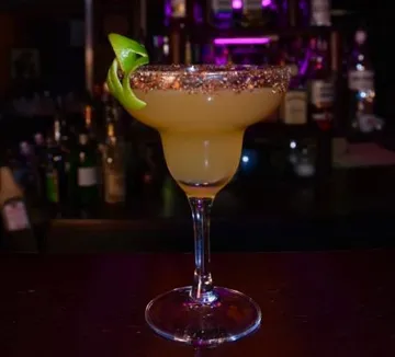 Cocktail glass with lime on bar counter.