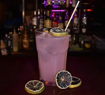 Pink drink with lemons on bar counter.