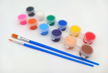 Colorful paint pots with brushes on white background.
