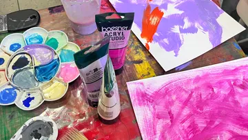 Farbflaschen und Palette auf Tisch.