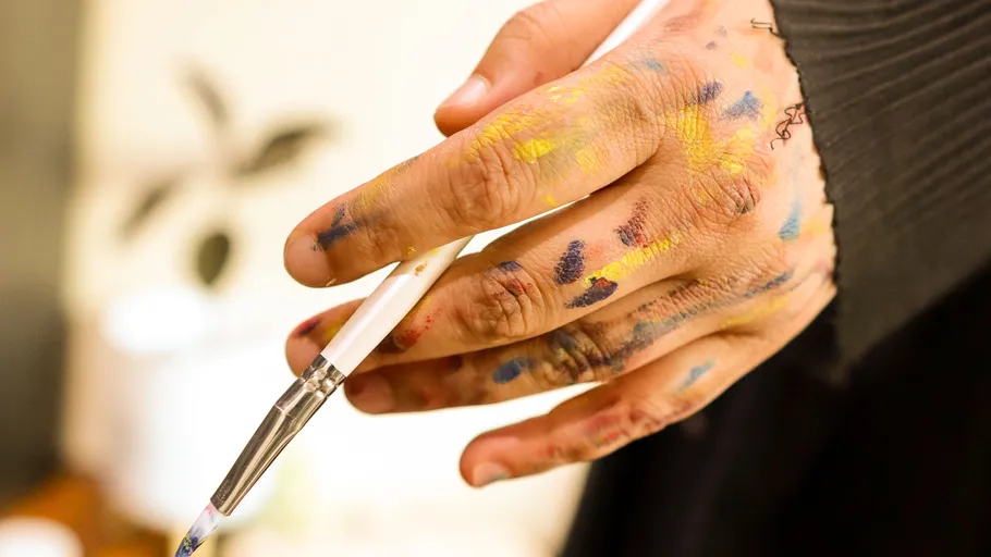 Mit Farbe bedeckte Hand hält Pinsel innen.