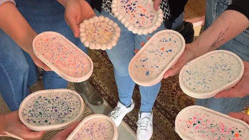 Hände halten bunte Terrazzo-Tabletts.