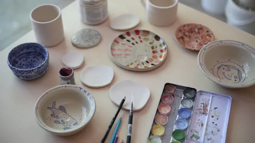 Ceramic bowls on table with paint supplies.