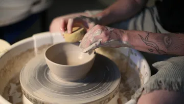 Person shaping pottery on a spinning wheel.