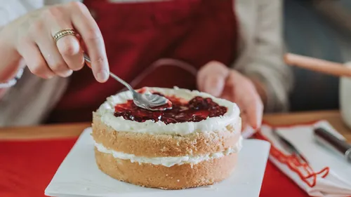 Person verziert Kuchen mit Löffel in Küche.