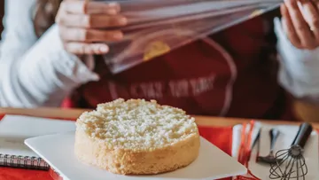 Person wrapping cake in plastic wrap.