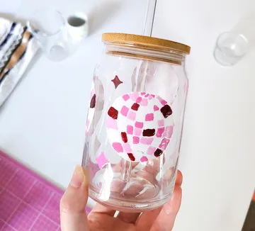 Painted jar held by hand on table.