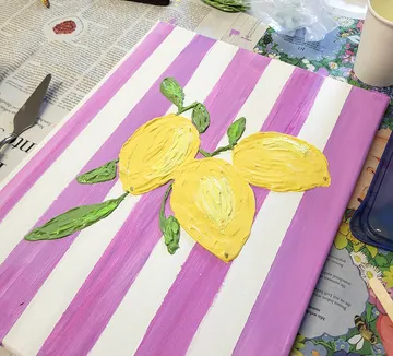 Canvas with lemons painted, striped background.