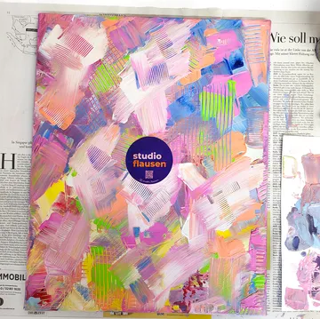 Abstract painting with colorful strokes on newspaper.