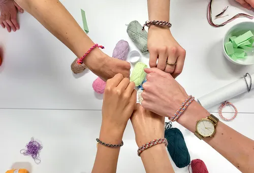 Hände zeigen Armbänder, Bastelumgebung.