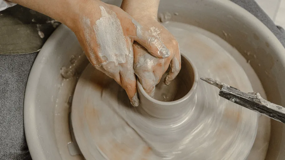 Hands shaping clay on a pottery wheel.