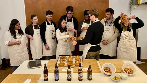 Menschen mit Schürzen genießen Brezeln drinnen.