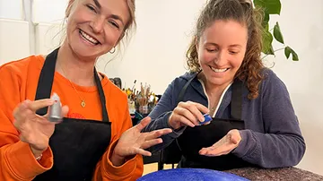 Two women laughing while crafting together.