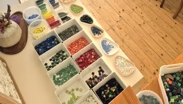 Colorful mosaic tiles organized by color on table.