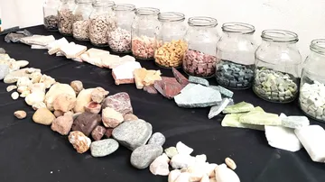 Jars with colorful stones on black table.