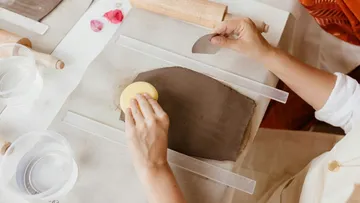 Hands smoothing clay slab with sponge.