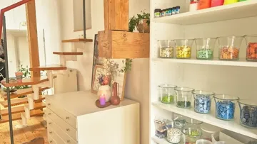 Glass jars on shelves in cozy workspace.