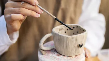 Hand painting ceramic cup in studio.