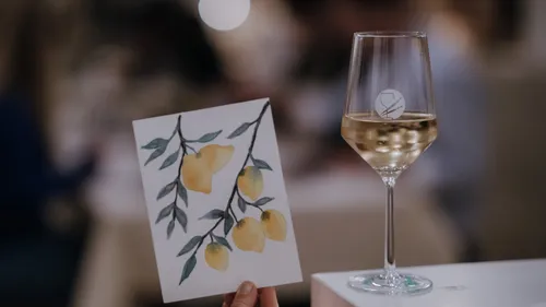 Painting of lemons held beside wine glass.