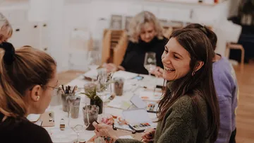 People laughing around a table, dining together.