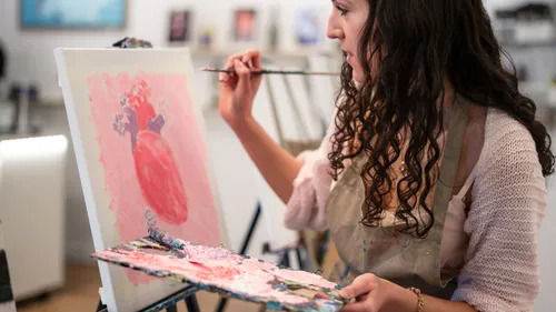 Woman painting heart on canvas in studio.