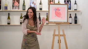 Woman presenting painting in wine store.