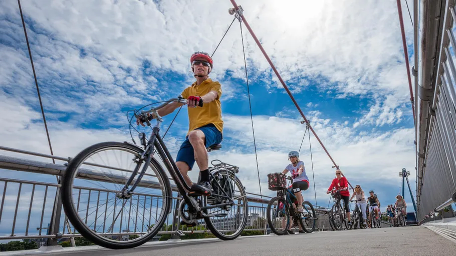 Radfahrer fahren mit Fahrrädern auf einer Brücke.