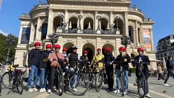 Gruppe mit Fahrrädern vor historischem Gebäude.