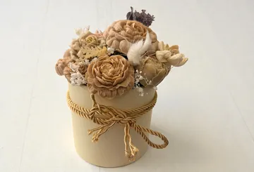 Dried flower arrangement in a beige vase.