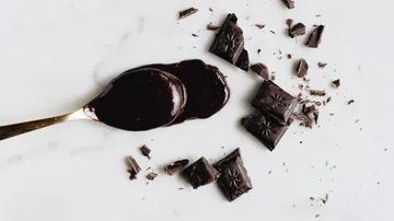 Löffel mit geschmolzener Schokolade auf Marmor.